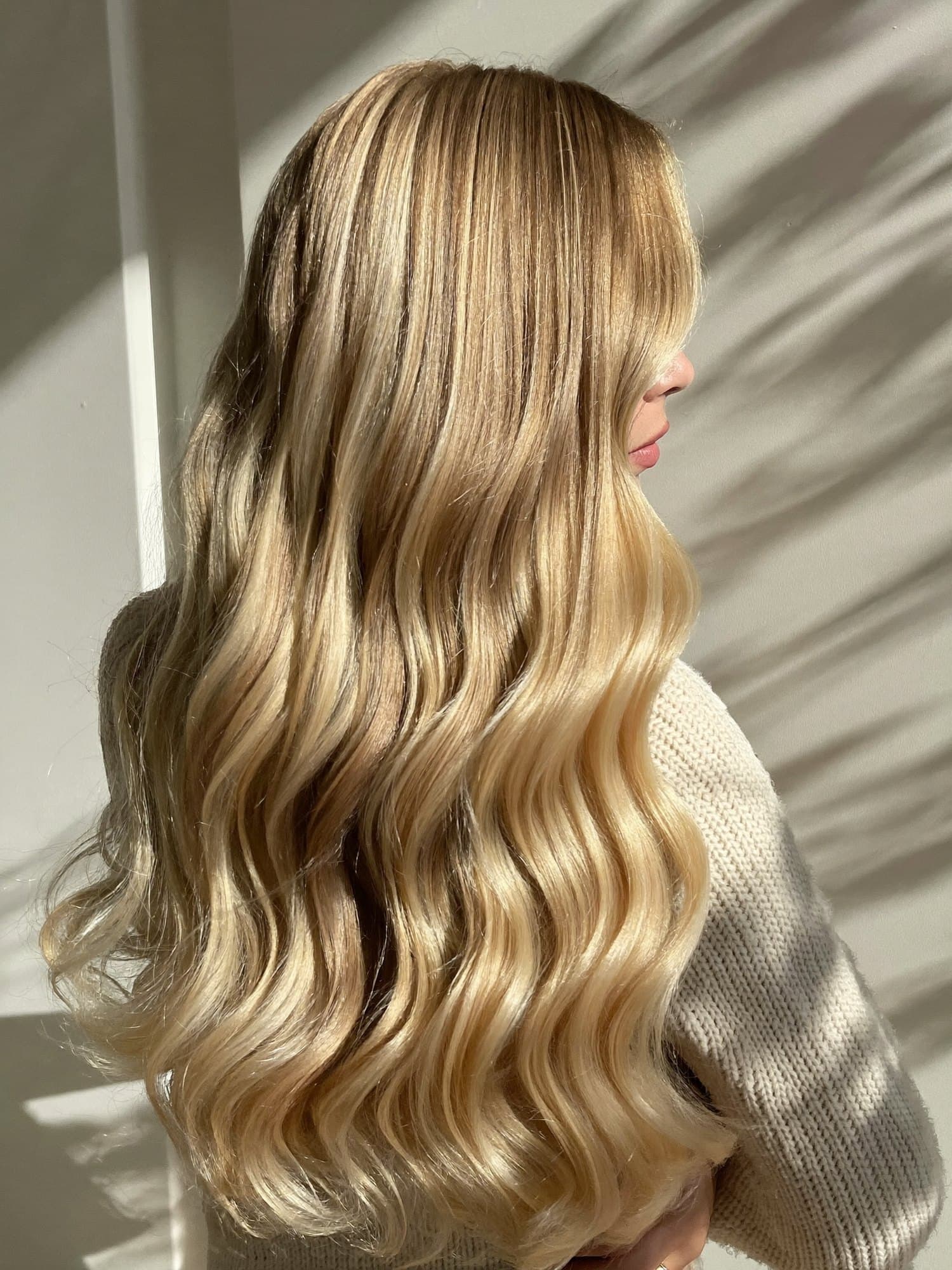 Long, glossy blonde waves seen from behind, lit by low sunshine.