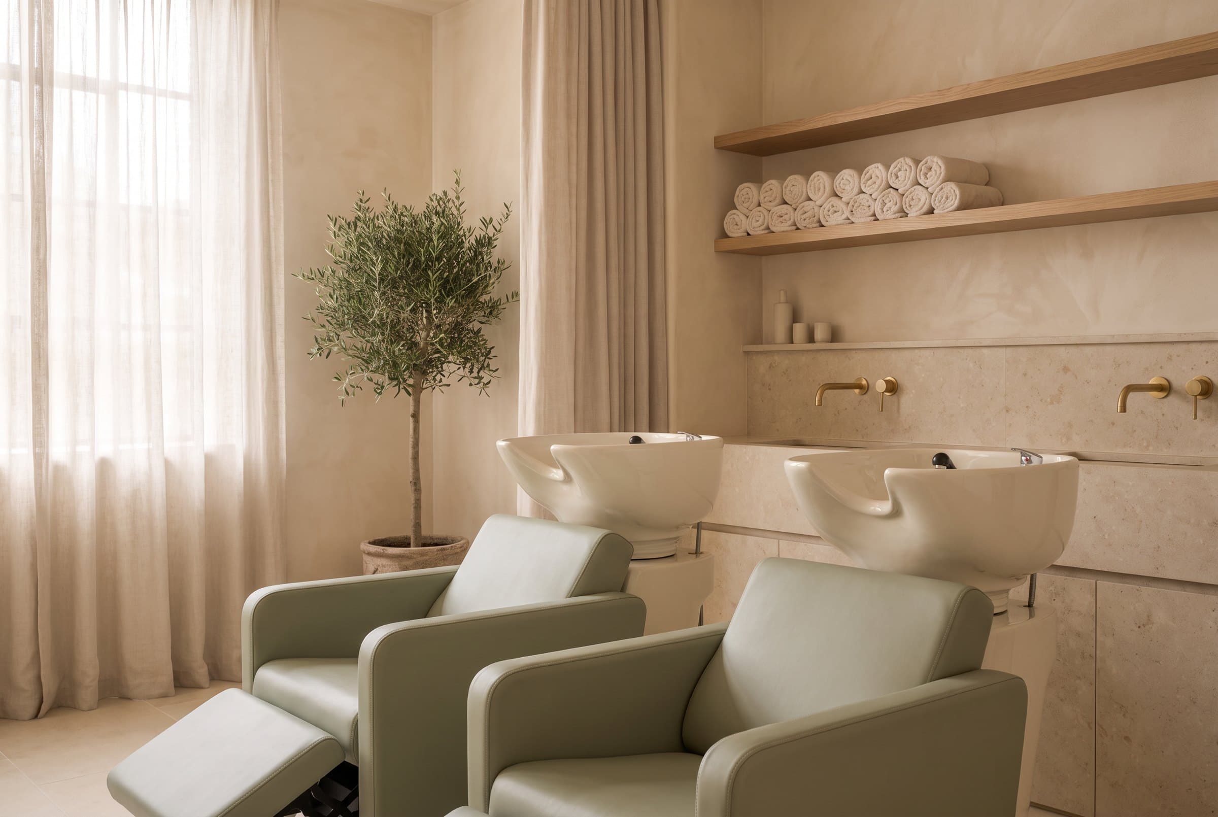 A calm backwash area with ivory ceramic basins and sage-green reclining chairs.